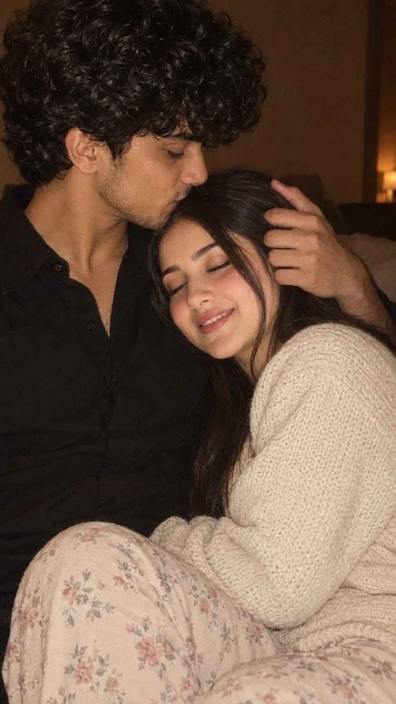 Young couple sharing a cozy forehead kiss while sitting together indoors